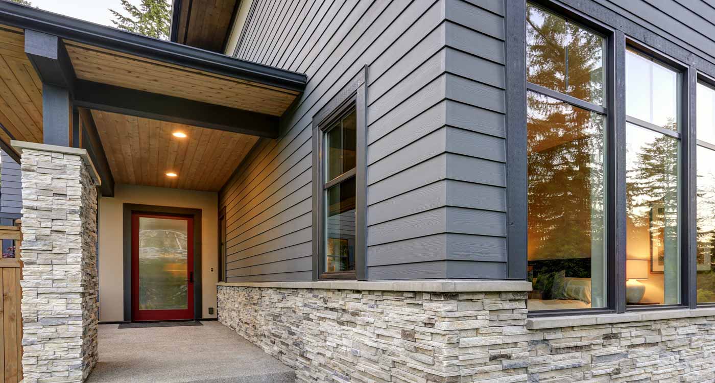 A two-story house with gray siding done by Refresh Exteriors, white trim, and a blue front door