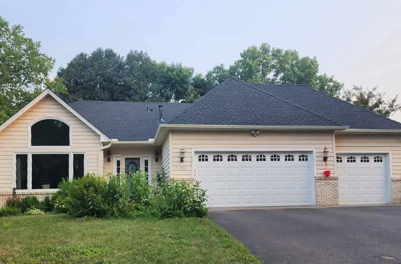 An after photo of A newly roofed two-story house with a navy blue exterior and white trim. Renovated by Refresh Exteriors LLC Minnesota’s most referred roofing contractor